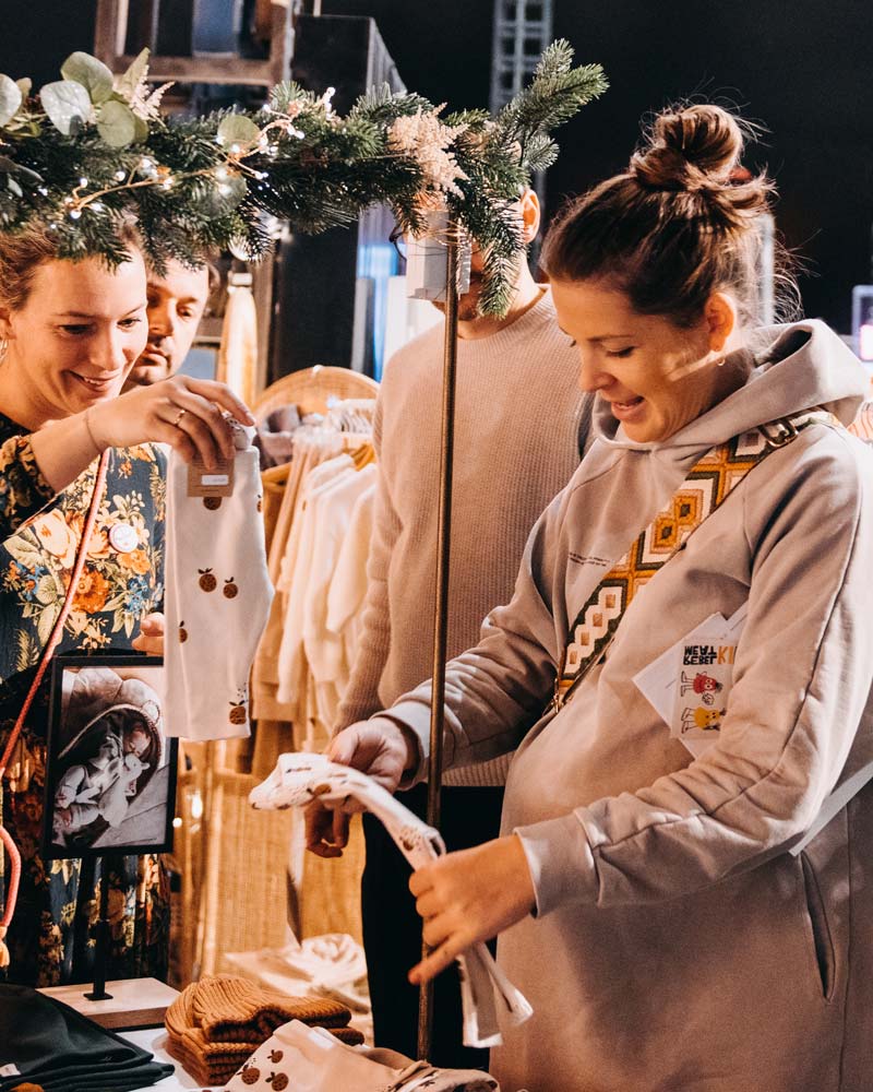Visitors browsing children's clothing at a festive stand