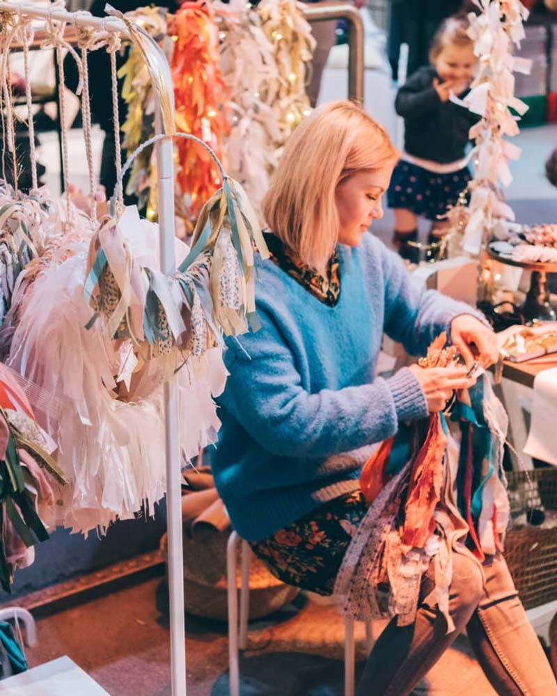Maker arranging handmade ribbon garlands at her stand