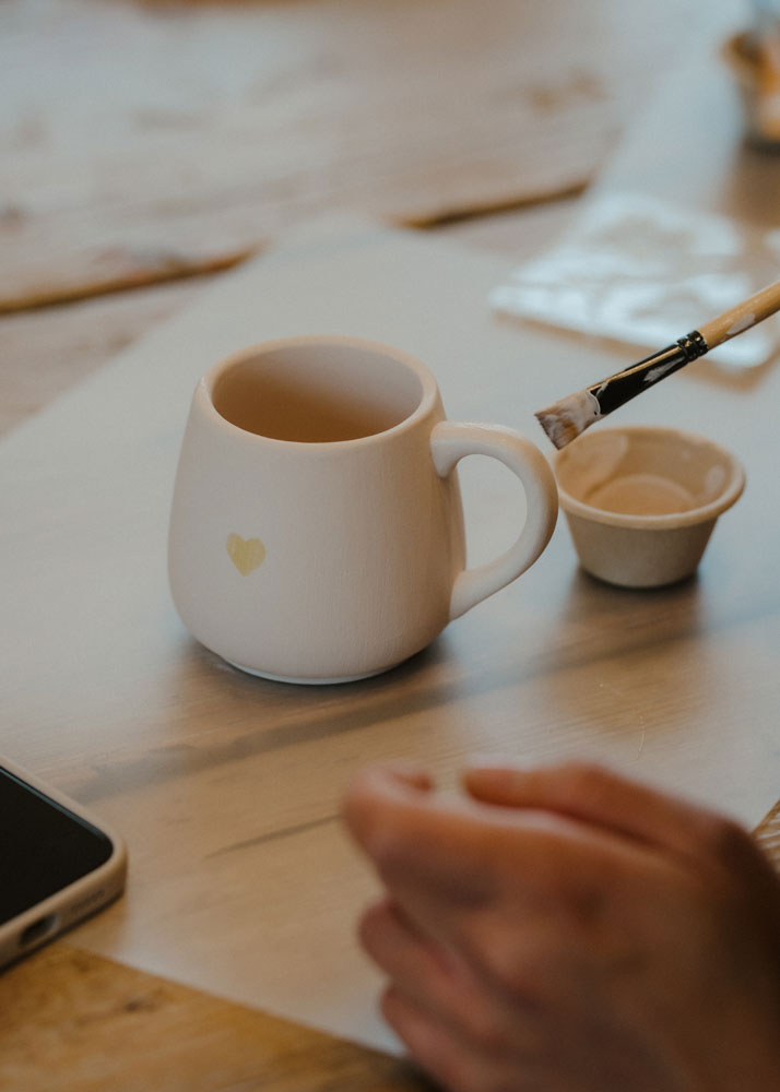 Hand-painting a ceramic mug at a DIY station